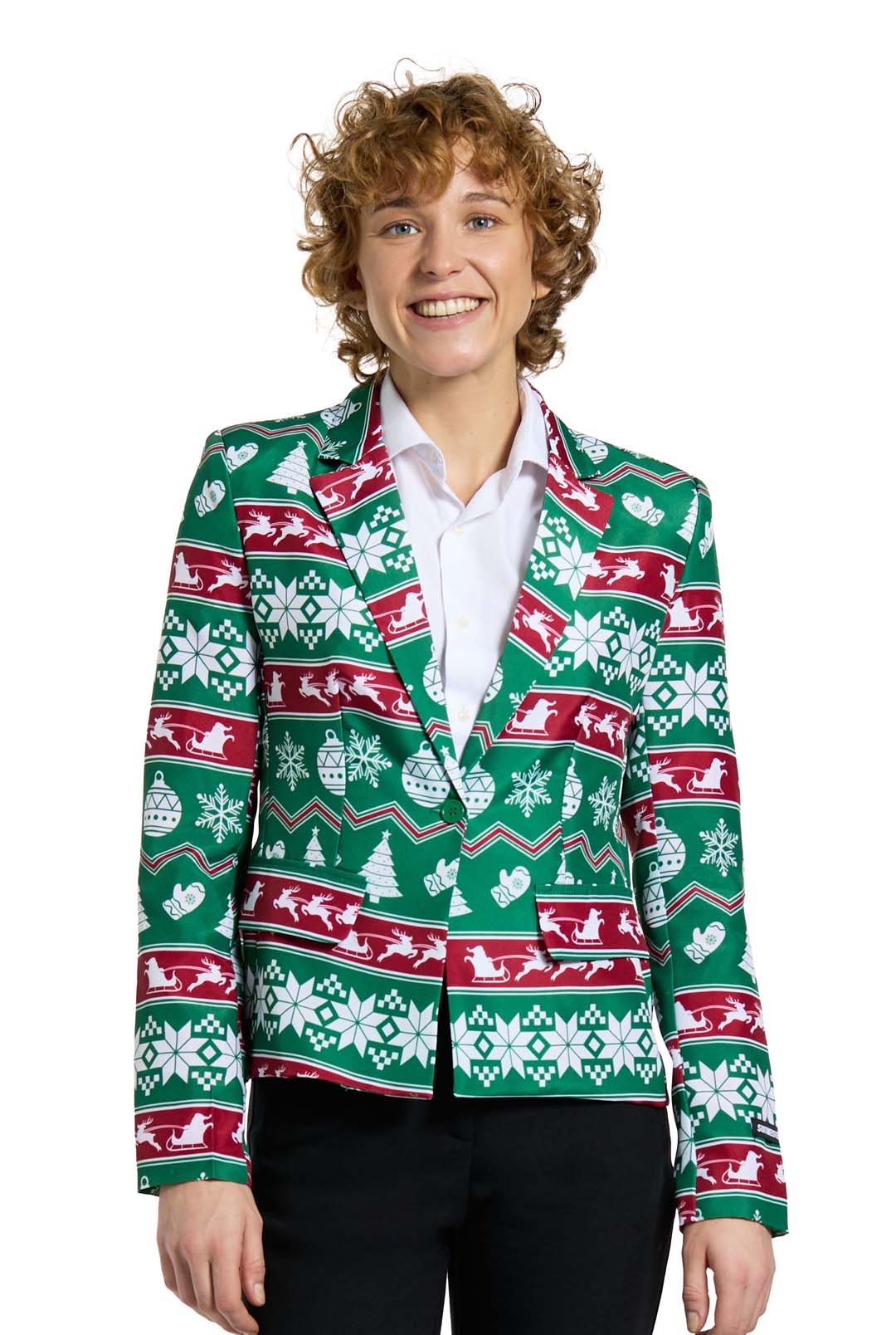 A person with curly hair is sporting the festive Christmas Green Nordic Jacket by Suitmeister, which features delightful Christmas patterns in green, red, and white such as snowflakes, trees, and reindeer. They are smiling while dressed in black pants and a white shirt.