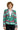 A person with curly hair is sporting the festive Christmas Green Nordic Jacket by Suitmeister, which features delightful Christmas patterns in green, red, and white such as snowflakes, trees, and reindeer. They are smiling while dressed in black pants and a white shirt.