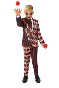 A child in a red and black clown-patterned suit tossing a red juggling ball upward while wearing black shoes.