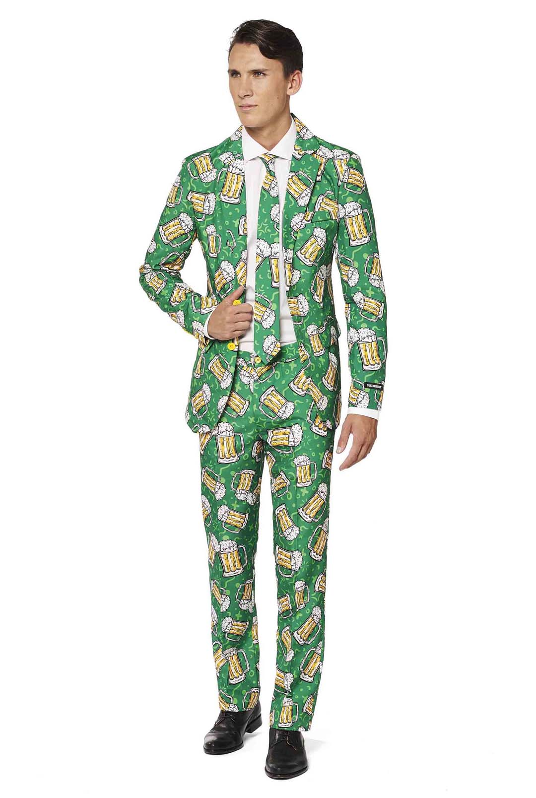 A person dressed in the Suitmeister Beer Suit, featuring a vibrant green pattern of beer mugs perfect for a festive or themed occasion. The ensemble includes a matching tie and white shirt, complemented by black shoes.
