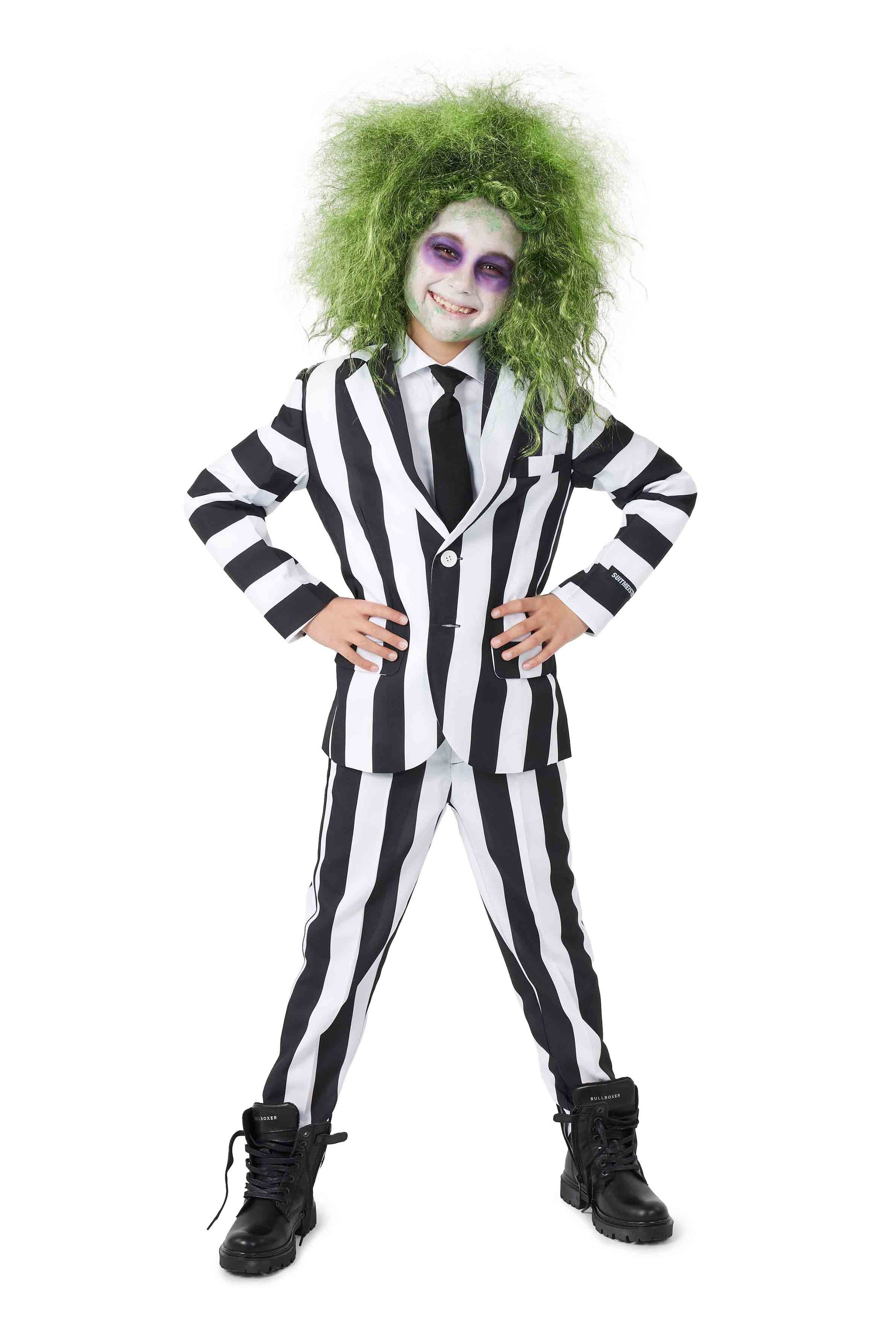 Dressed in the Suitmeister Beetlejuice ensemble, featuring a black and white striped suit with a matching tie and large black boots, this person completes the look with green curly hair and face makeup, creating a playful or spooky costume.