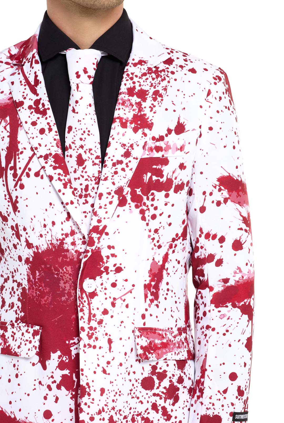The individual is dressed in a Suitmeister "Bloody Suit White," featuring a white background with red paint splatter details. The shirt underneath is black, and the tie complements the suit by showcasing the same splatter design. Only the upper body is visible.