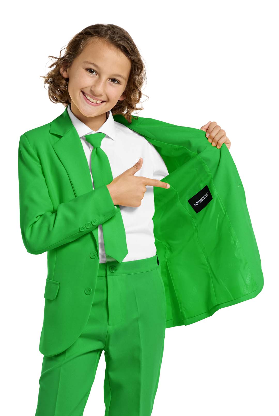A young person with wavy hair smiles at the camera, wearing a Suitmeister Solid Green suit, white shirt, and green tie. They stand against a white background with one hand in their pocket.