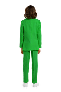 A young person with wavy hair smiles at the camera, wearing a Suitmeister Solid Green suit, white shirt, and green tie. They stand against a white background with one hand in their pocket.