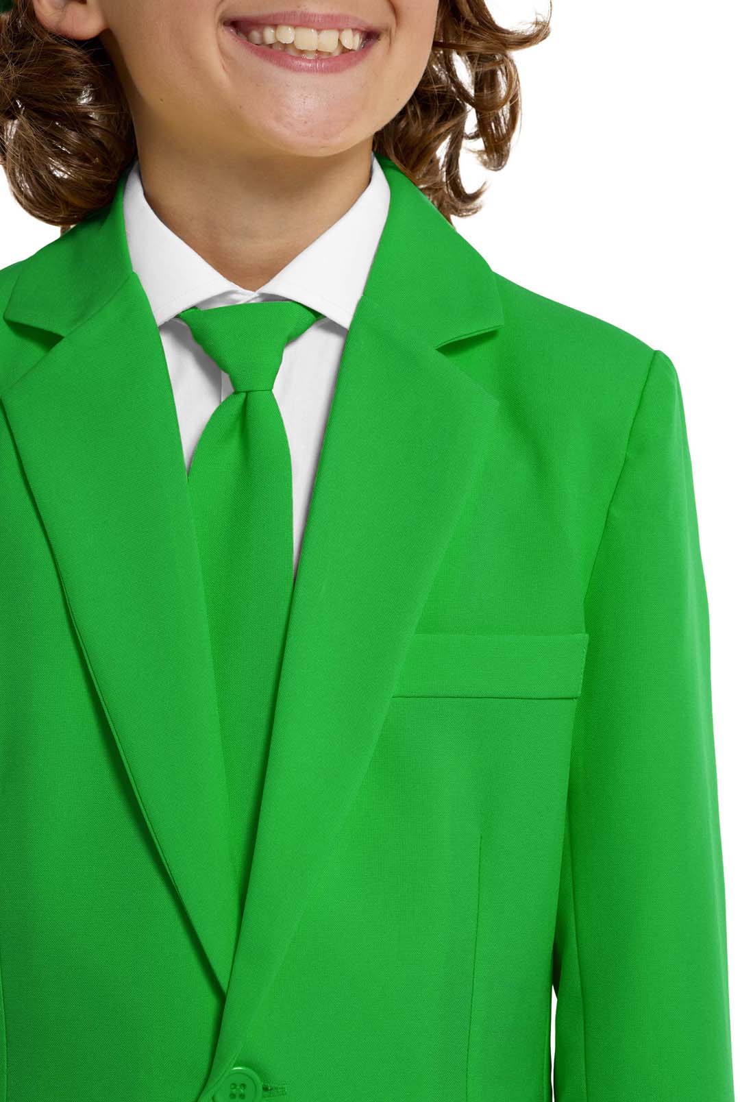 A young person with wavy hair smiles at the camera, wearing a Suitmeister Solid Green suit, white shirt, and green tie. They stand against a white background with one hand in their pocket.