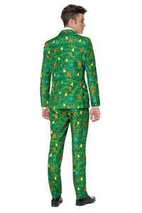 Dressed in Suitmeister's "Christmas Green Tree," a person with colorful dinosaur prints on their vibrant green suit stands facing away, gazing over their right shoulder, and completes the look with black shoes.