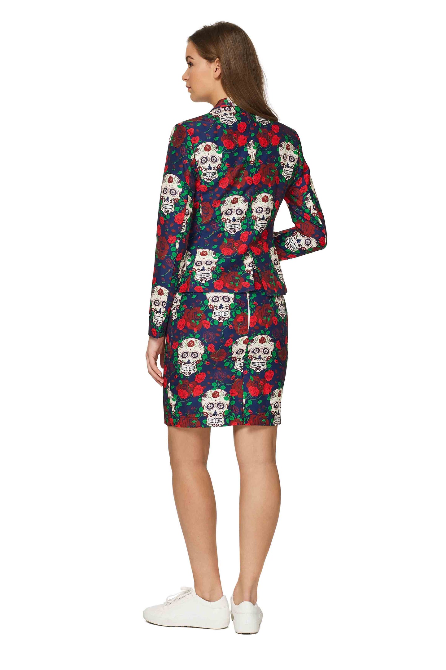 A person is wearing the Suitmeister "Day of the Dead - Halloween outfit," which features a vibrant jacket and skirt adorned with skulls and floral designs. The individual is facing away, highlighting the back of the ensemble, and pairing it with white sneakers.