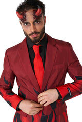Dressed in the Devil Red ensemble from Suitmeister, a man sports a burgundy suit adorned with black accents and paired with a striking red tie. Complementing his devilish look are devil horn accessories and forehead makeup, while his black shirt provides a bold contrast to the fiery theme of his attire.