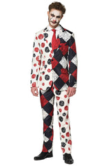 A man is wearing a Halloween Clown Vintage suit by Suitmeister, showcasing a split-pattern design in red, black, and white with circular and checkered motifs. He complements his outfit with clown-like face paint highlighting exaggerated eyes and mouth, paired with a red tie and black shoes.