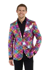 Image with white background and man wearing rainbow colored sequins blazer. Man also wearing black shirt and black pants. One hand in his pocket and  looking in the camera.