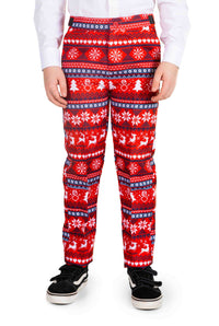 A child dressed in Suitmeister's "Nordic Pixel Red" pants, featuring a festive Christmas pattern of snowflakes, trees, and reindeer, paired with a white shirt and black sneakers.