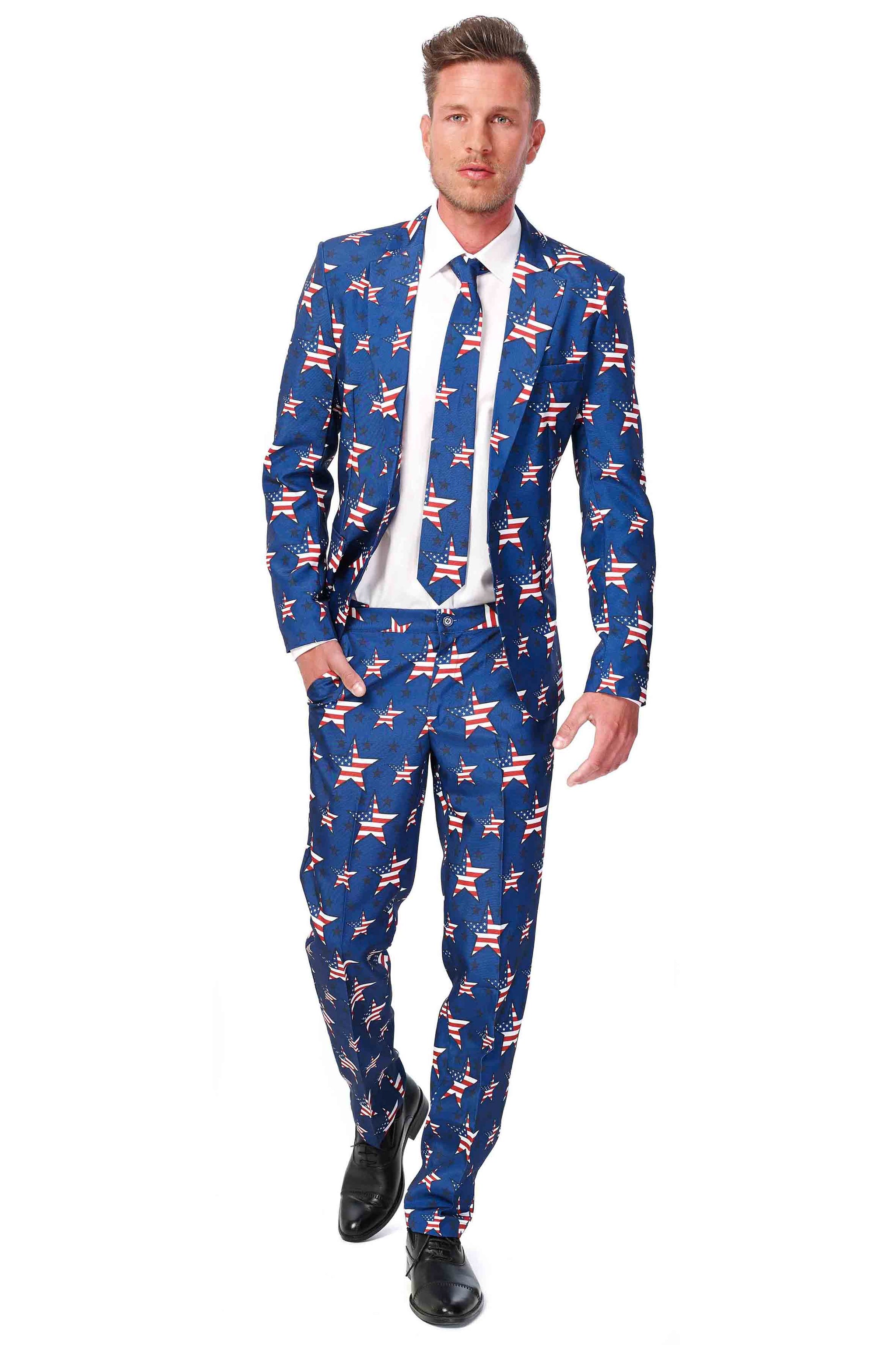 A man walks confidently wearing the Suitmeister USA Stars and Stripes suit, featuring a pattern of white stars and red stripes reminiscent of the American flag. He pairs it with a white shirt, matching tie, and black shoes.